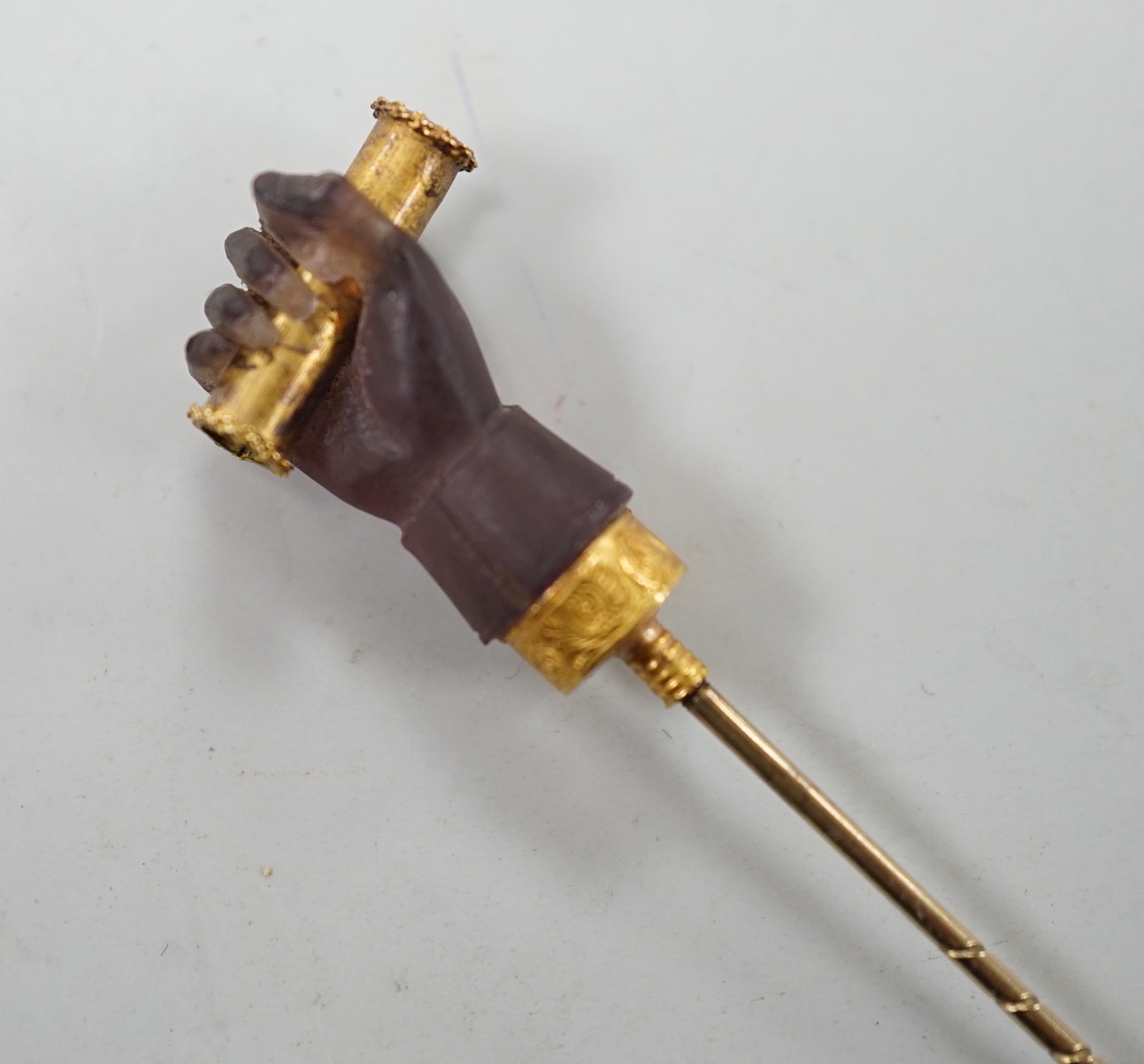 A cased 19th century yellow metal and amethyst glass? set Stanhope stick pin, modelled as hand holding a spyglass, 85mm, the lens depicting the bust of military? gentleman.